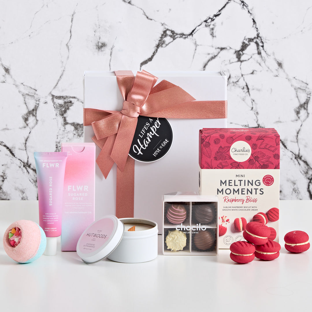 With love a gift hamper that includes, hutwoods champgane and strawberries candle. hand cream, bath bomb, chocilo truffles and mini melting moments.