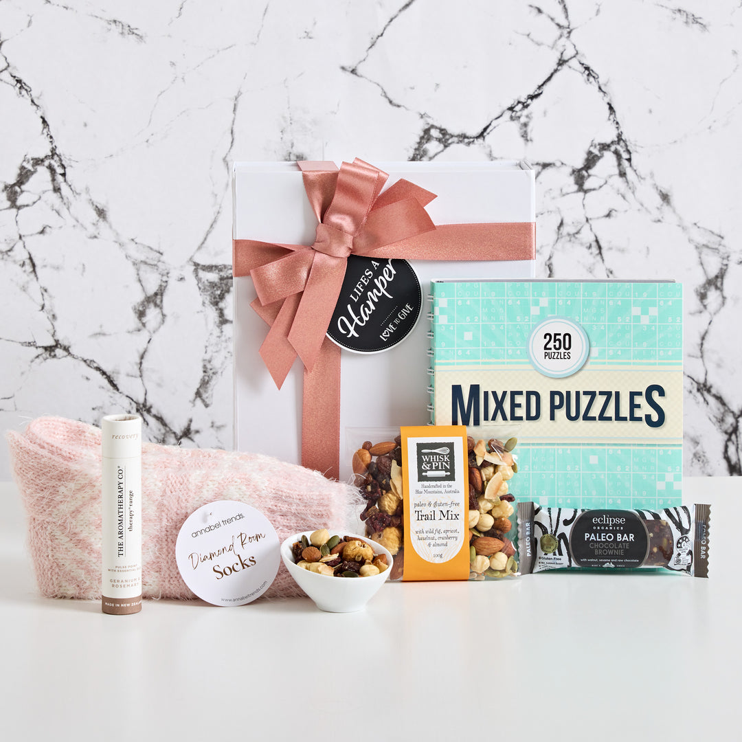 Treat her to a cozy get well gift hamper. Included is a mixed puzzle book, warm bed socks, whisk & pin trail mic, pulse point and an eclipse paleo bar. A gift that will make her better in no time.