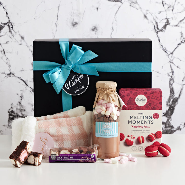 Sweet Comfort hamper comes in black box with blue ribbon. It includes soft bed socks, hot chocolate mix, raspberry melting moments and milk rocky road.