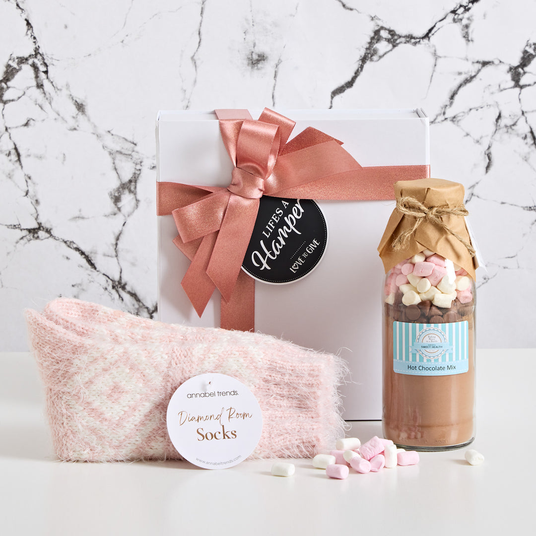Warm hug comes presented in a black magnetic box with pink ribbon. It includes nice lounge socks and a delicious hot chocolate mix. This warm hug gift hamper makes a great get well soon gift hamper